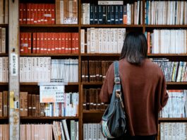 woman wearing brown shirt carrying black leather bag on front of library books