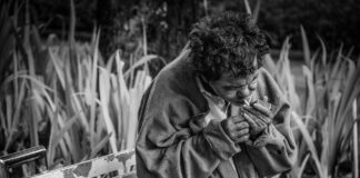 grayscale photo of man with cigarette sitting on bench