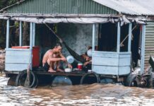 man pouring water from dipper on blue and grey house