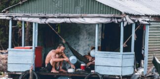 man pouring water from dipper on blue and grey house