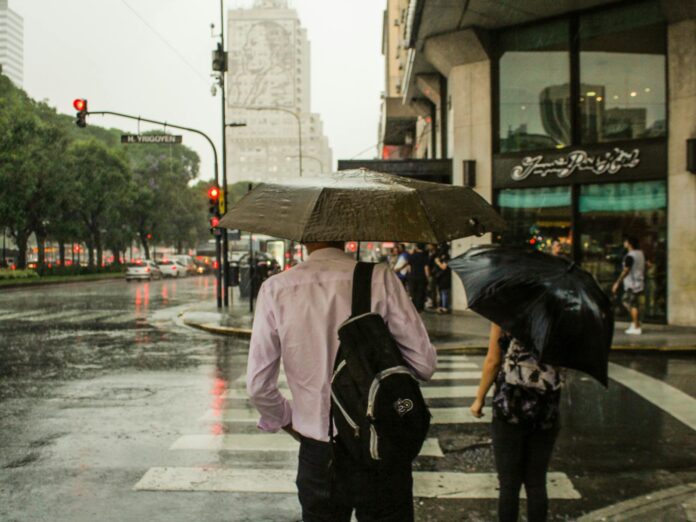 man wearing dress shirt holding an umbrella