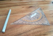 gray pencil and triangular ruler on brown wooden surface