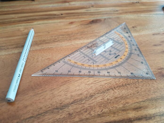 gray pencil and triangular ruler on brown wooden surface