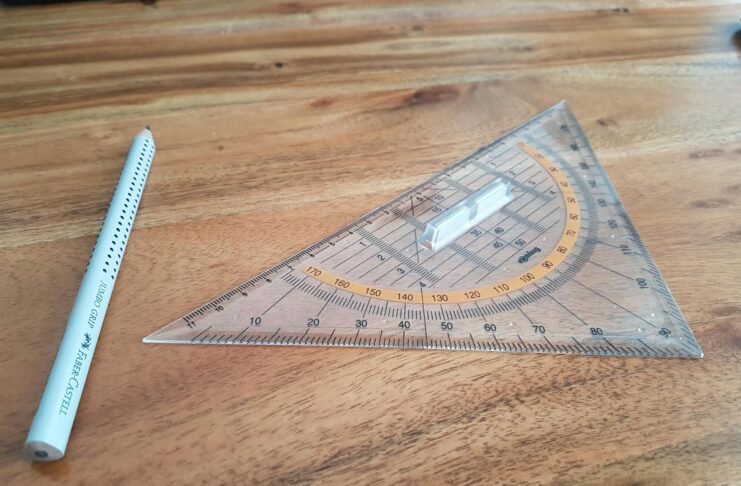 gray pencil and triangular ruler on brown wooden surface